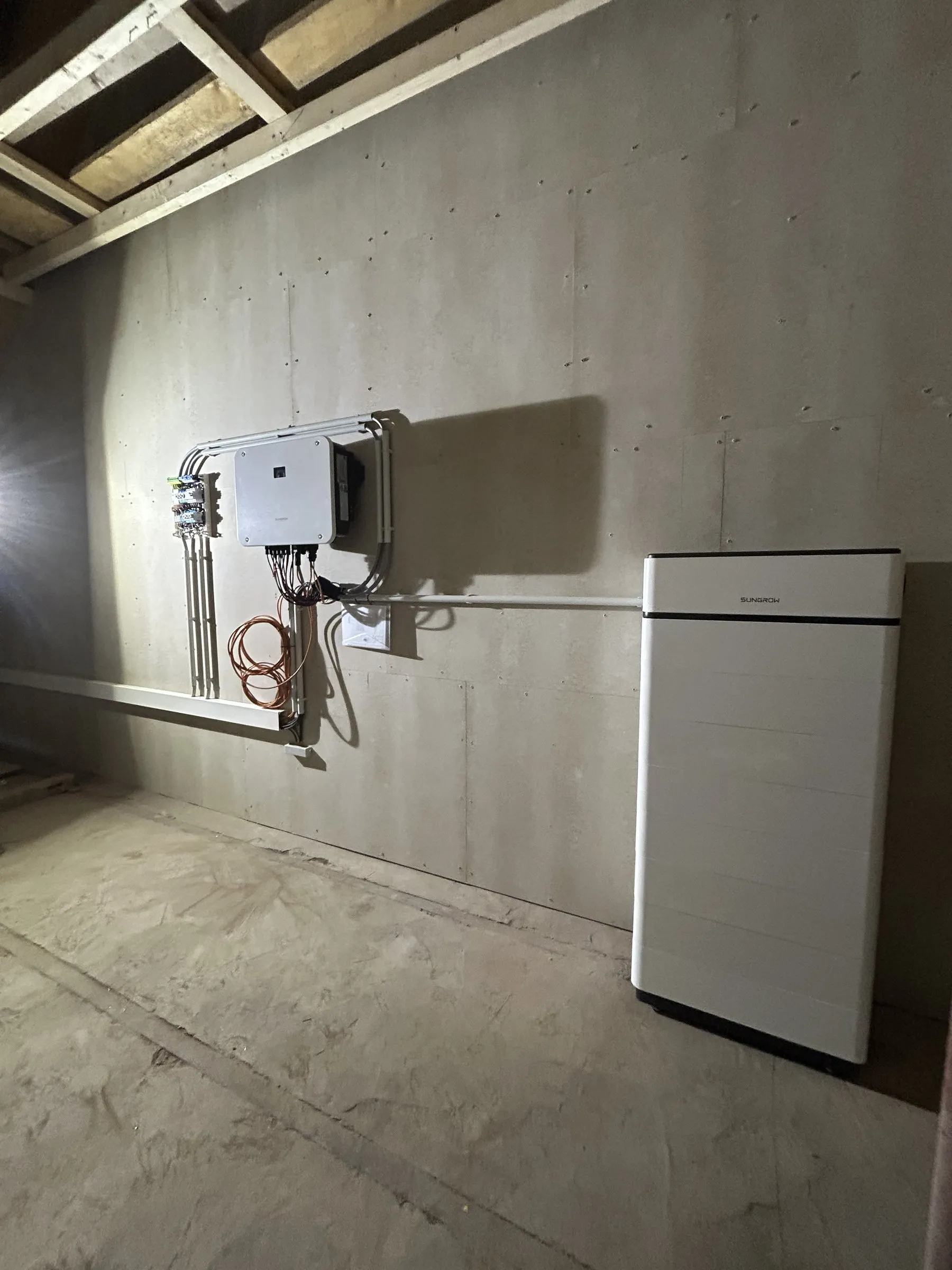 Wechselrichter und Speicher an einer Betonwand im Neubau