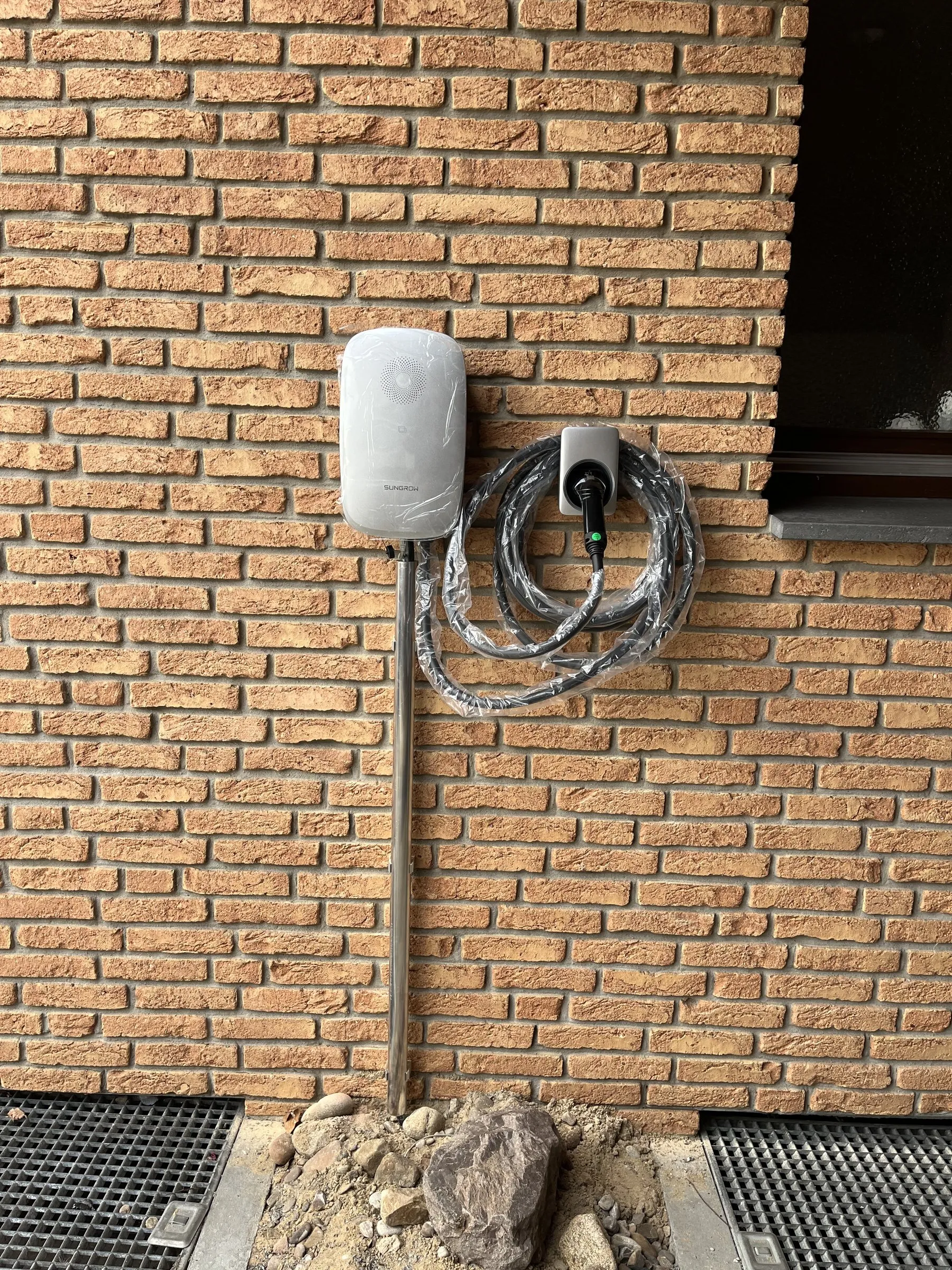 Wallbox mit Ladekabel an einer roten Klinkerwand